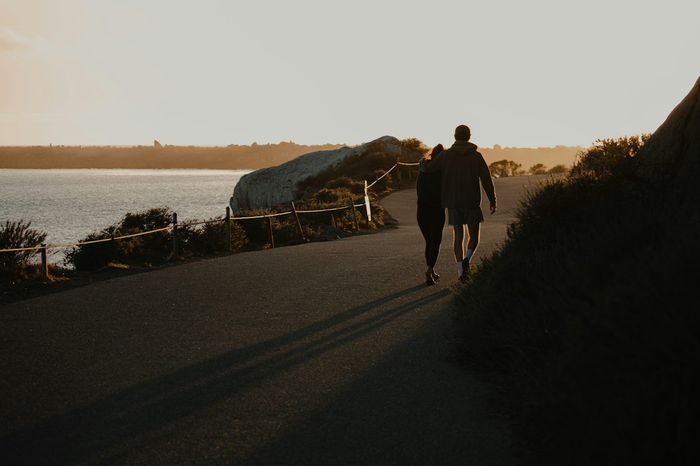 Due persone camminano lungo un sentiero costiero vicino all'oceano.