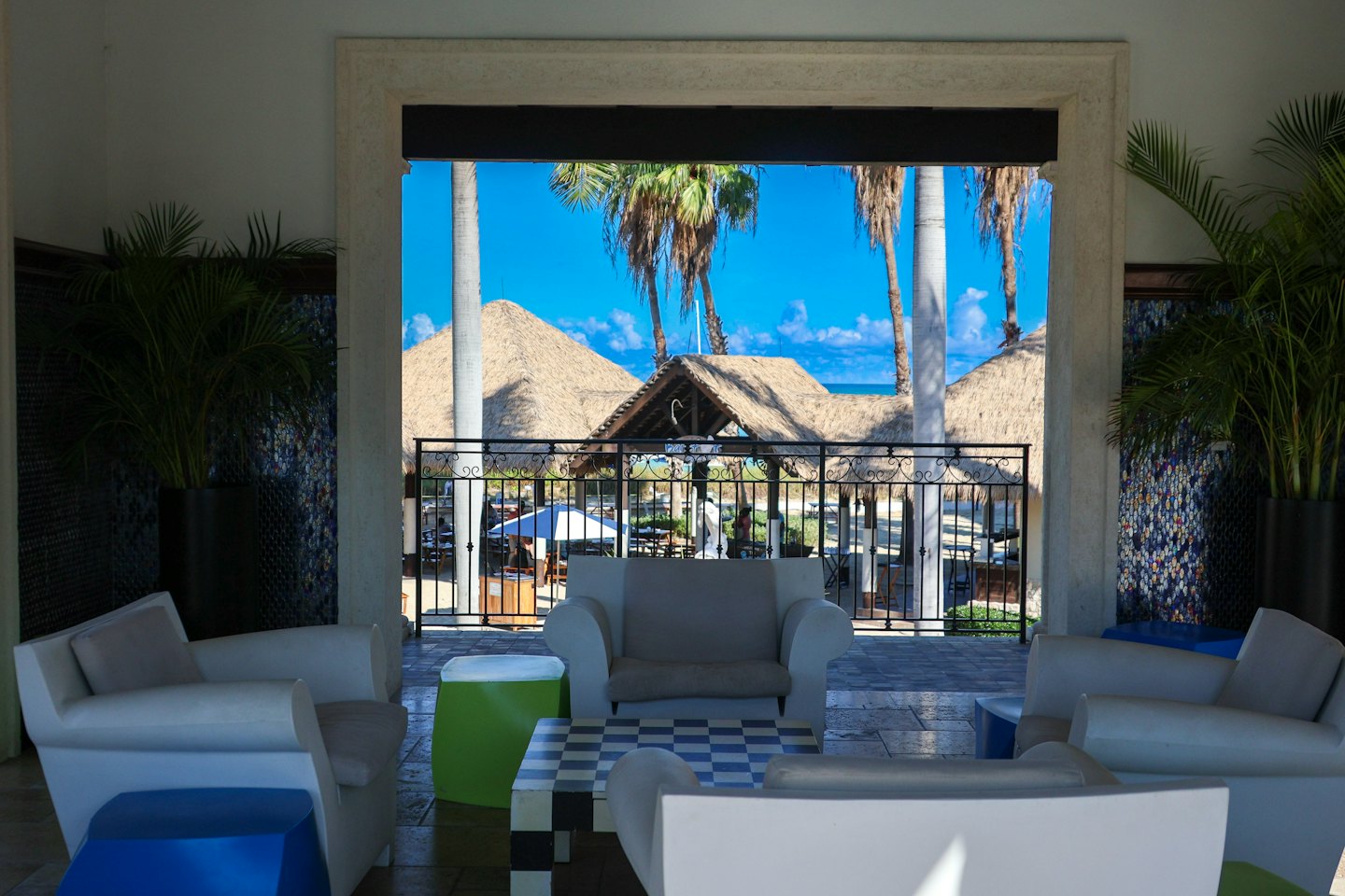 Salotto interno con sedie contemporanee si affaccia su cabine da spiaggia e oceano.